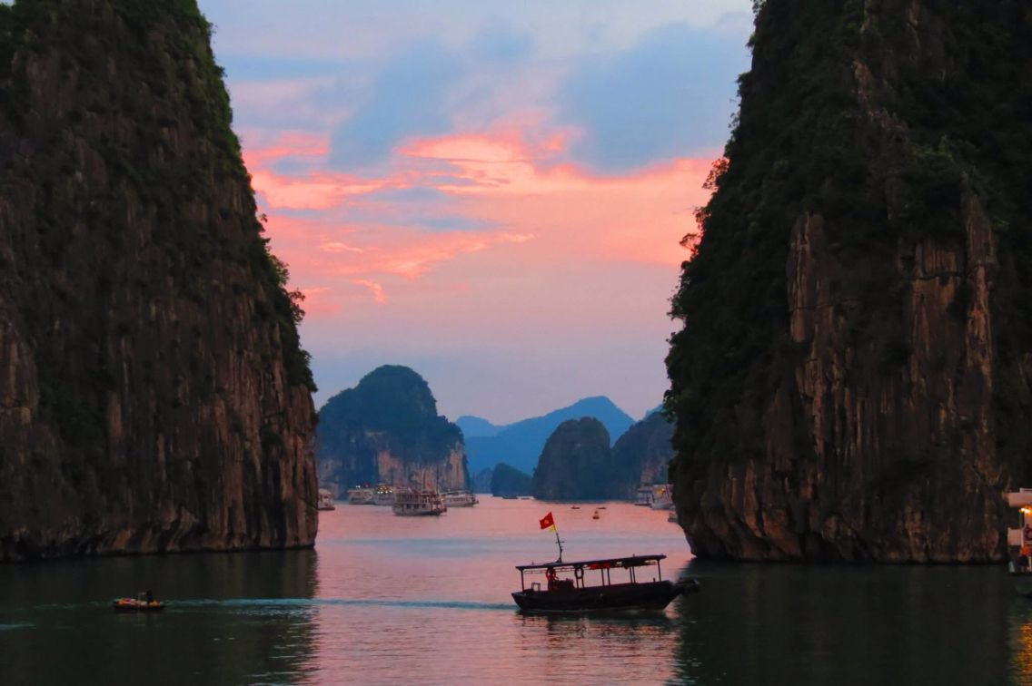 Thuyền trên vịnh Hạ Long giữa những đảo đá lúc hoàng hôn
